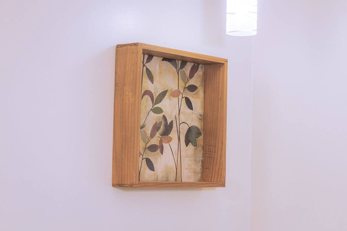 A framed artwork with a plant design on a plain wall.