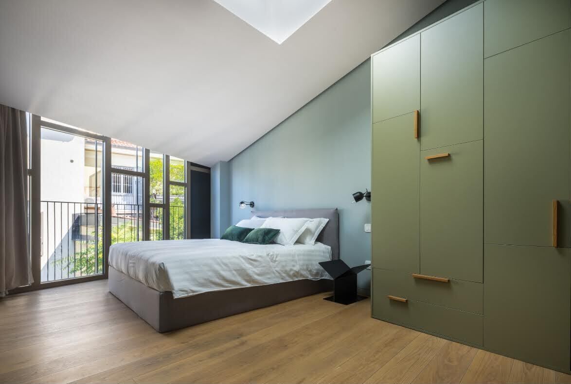 A modern bedroom with a large bed, a wardrobe, and a skylight.