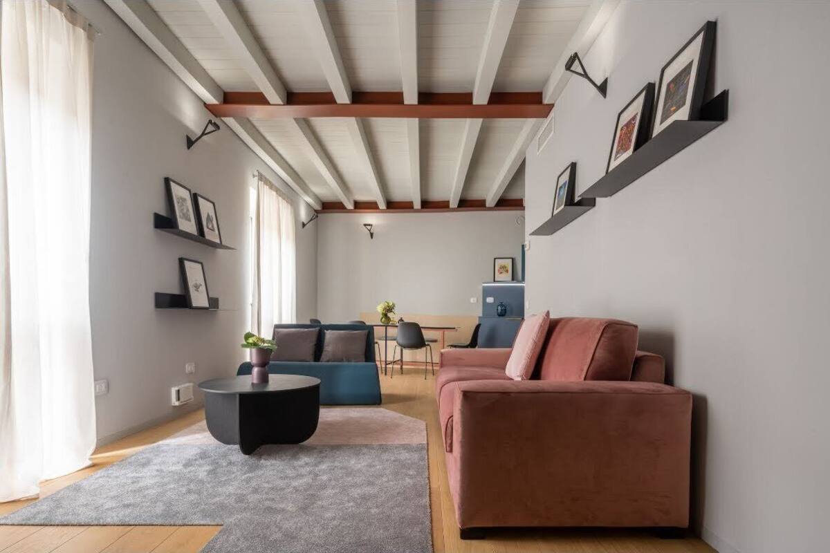 Un salon moderne avec un canapé, une table basse et, au fond, un coin repas.