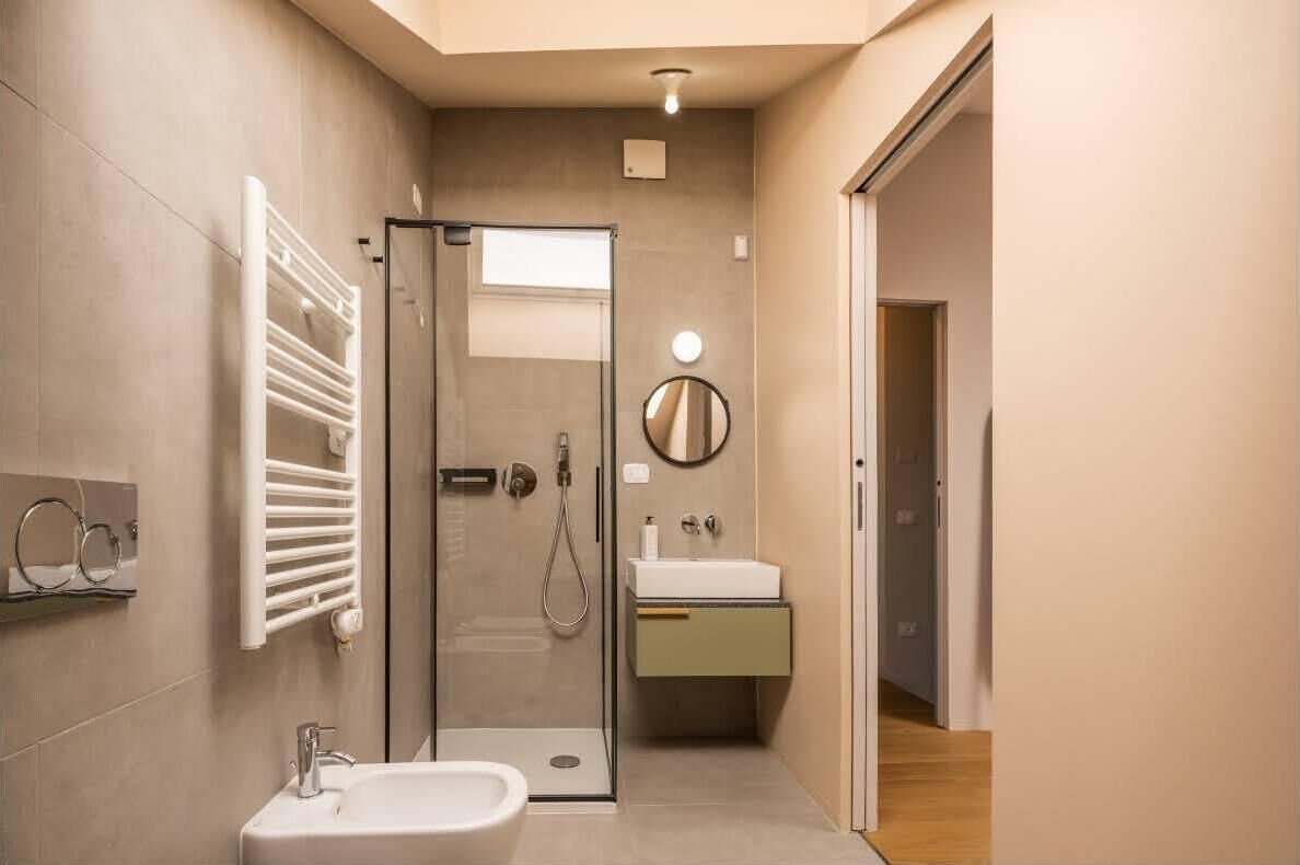 Ein modernes Badezimmer mit Duschkabine aus Glas, einem weißen Waschbecken und einem Handtuchhalter.