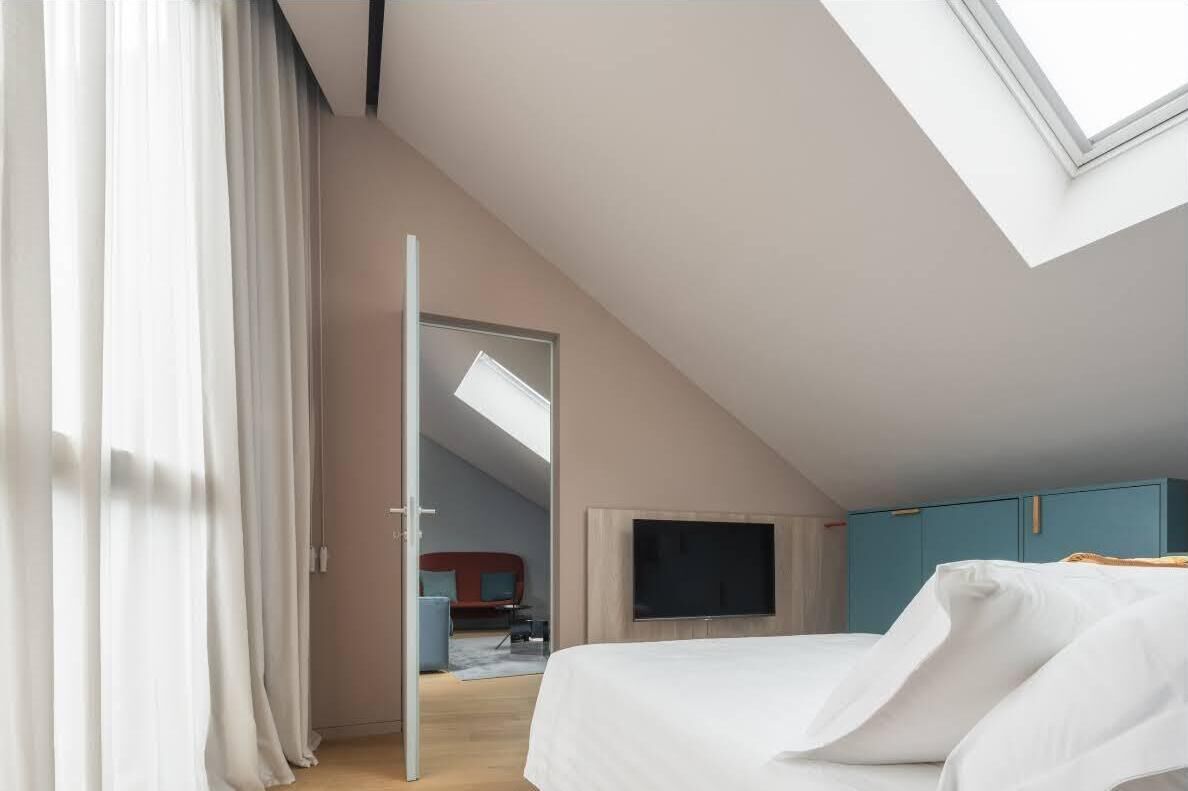 Een slaapkamer met dakraam, een bed, een televisie en een kledingkast.