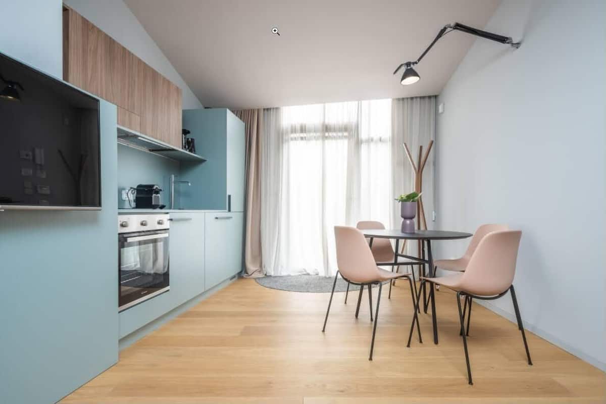 Une cuisine moderne dotée d’un four encastré et d’un coin repas avec une table et des chaises.