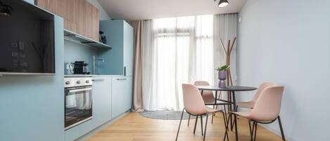 A modern kitchen with a built-in oven and a dining area with a table and chairs.