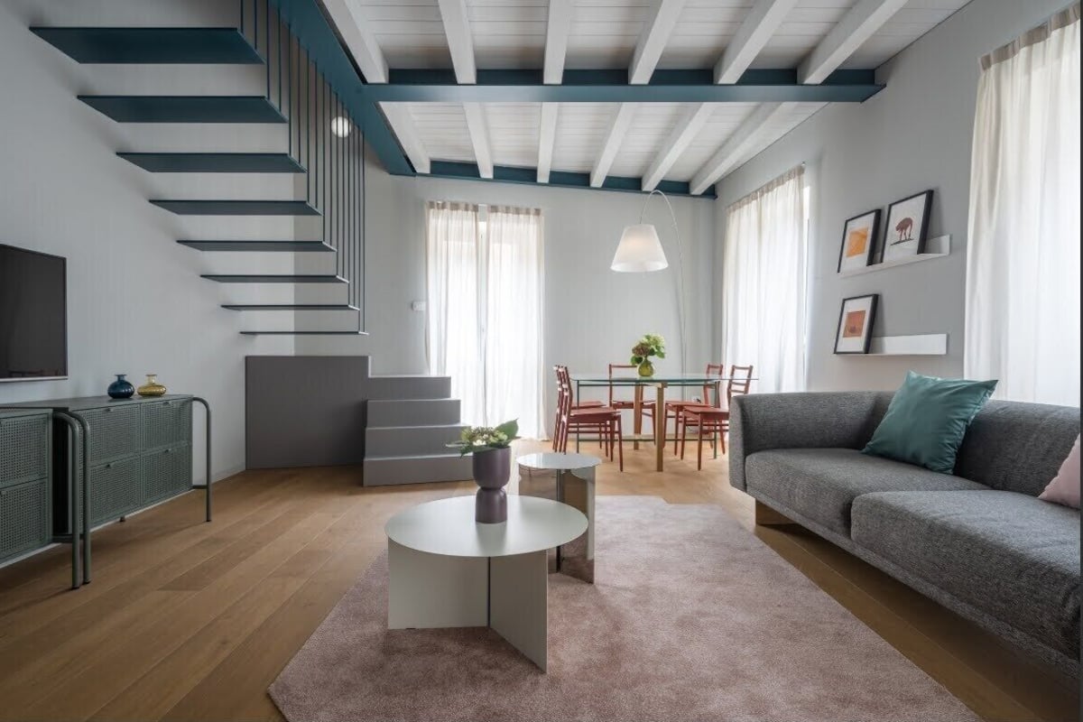 Un salon moderne avec un escalier, un coin repas et un canapé.