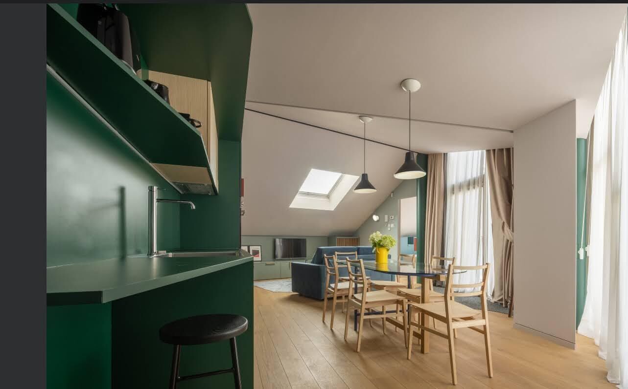 Una cocina moderna con comedor, que cuenta con tragaluces, paredes verdes y piso de madera.