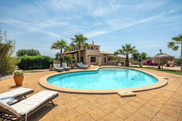 Relax by the pool surrounded by lush greenery and comfortable lounge chairs.