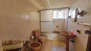 Ein Badezimmer mit zwei Toiletten, einem Waschbecken und einem Spiegel.