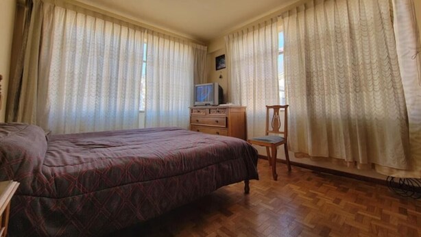 Ein Schlafzimmer mit einem Bett, einem Schreibtisch mit Fernseher und Vorhängen.