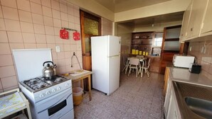 Eine kompakte Küche mit Gasherd, Kühlschrank, einem Esstisch mit Stühlen und einer Mikrowelle.