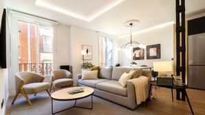 A modern living room with a sofa, two armchairs, a coffee table, and a small side table with a radio. - Justicia Royal by Madflats Collection (Madrid)