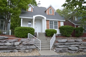 A two-story house with a front porch, stone steps, and a mailbox. - Huge 4BDR Cottage for 12 with game room in fabulous Stormy Point Village.  (Branson)