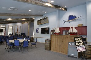 A room with a bar area, tables, chairs, and nautical decorations.