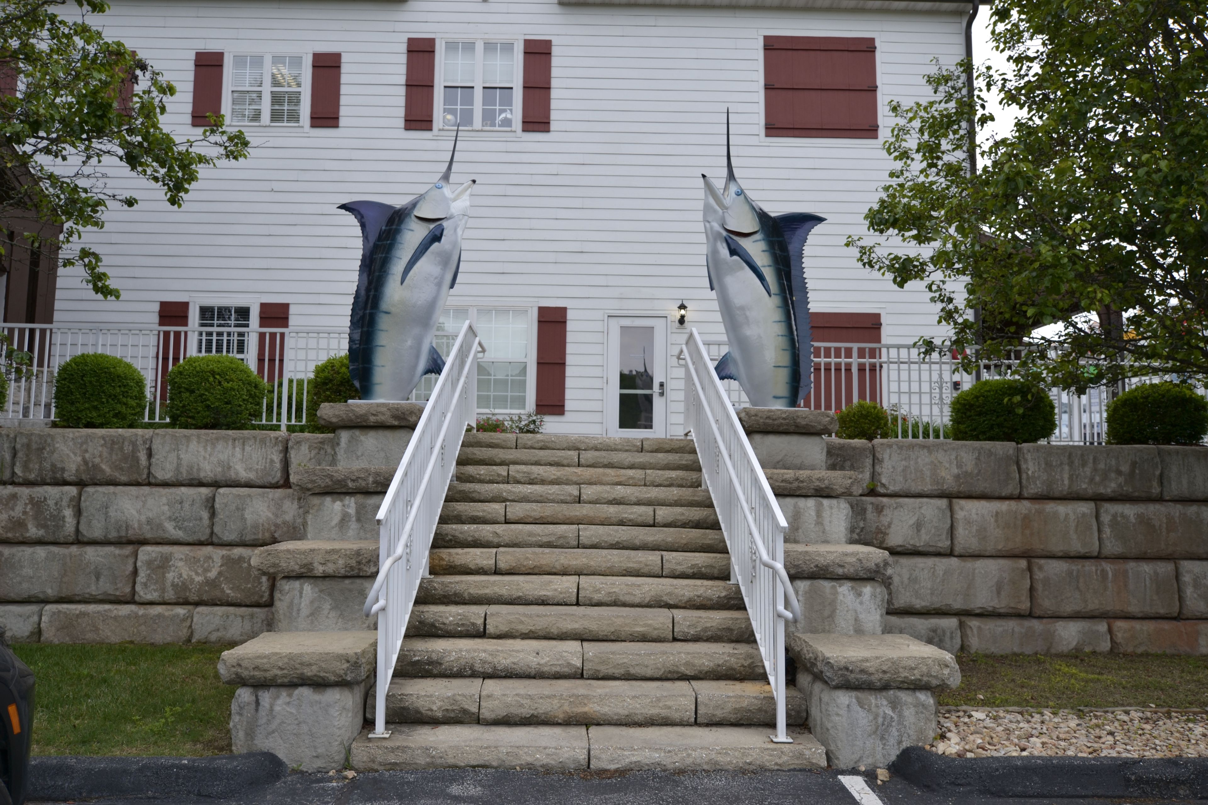 A building with a staircase leading to a door, flanked by two large shark sculptures.