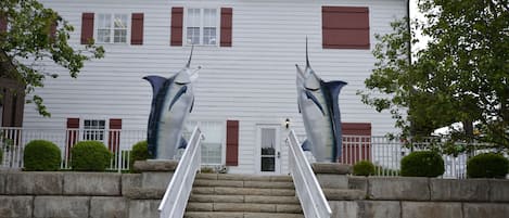 A building with a staircase leading to a door, flanked by two large shark sculptures.