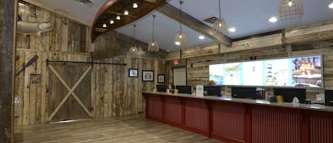 Un interno rustico con pareti in legno, una reception e lampade a sospensione.