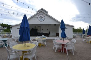 An outdoor patio area with tables and chairs, a covered seating area, and a building with a sign. - Huge 4BDR Cottage for 12 with game room in fabulous Stormy Point Village.  (Branson)