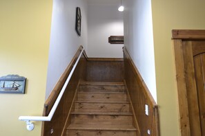 Uma escada de madeira com corrimão, uma placa fixada na parede e uma porta no final.