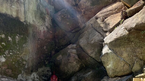 Una piscina con agua turquesa cristalina, rodeada de rocas grandes y una estructura roja en el centro.