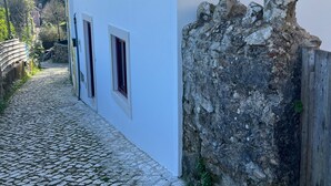 Un edificio blanco con tres ventanas y un camino de adoquines que lo conduce.