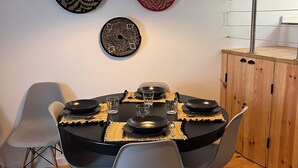 Un comedor con una mesa redonda dispuesta para seis personas, rodeada de sillas grises. Hay tres platos decorativos en la pared sobre la mesa.