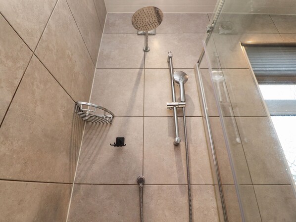 Une salle de bain équipée d’une douche, d’un pommeau de douche amovible et d’un flexible de douche.