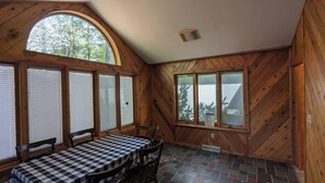 A room with a checkered table, wooden walls, and large windows with blinds. - The Lakeshore House (Niverville)