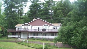 A two-story house with a balcony, located near a body of water. - The Lakeshore House (Niverville)