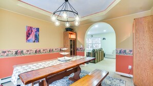 A dining area with a wooden table, benches, and a chandelier.