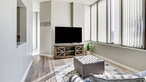 A living room with a flat-screen TV on a wooden cabinet, a grey sofa, and a patterned rug. - Columbia Vacation Rental - Walk to UofSC Campus! (Columbia)