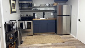 Een compacte keuken met moderne apparatuur, donkere kastjes en een houten aanrecht.
