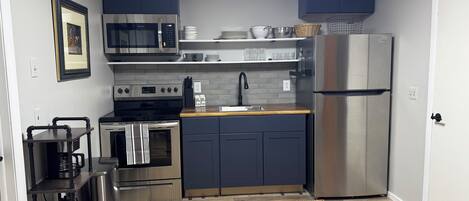 Una cocina compacta con electrodomésticos modernos, gabinetes oscuros y una encimera de madera.