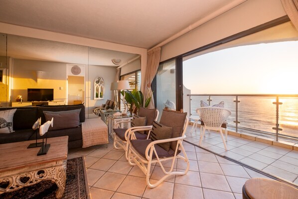 Un salón moderno con sofá, una mesa de centro y un balcón con vistas al mar.