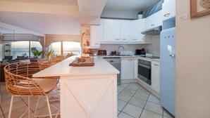 A modern kitchen with white cabinetry, a central island with seating, and a view of the cityscape through large windows.