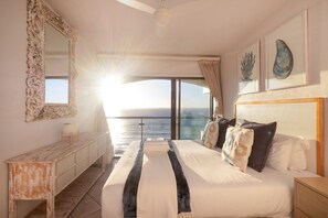 Ein Schlafzimmer mit einem großen Bett, einem Schminktisch und Blick aufs Meer.