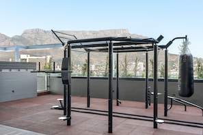 An outdoor gym with a punching bag, pull-up bar, and weight bench.