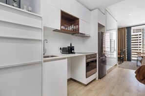 Eine moderne Küche mit weißen Schränken, einem eingebauten Ofen und einem Edelstahl-Kühlschrank.