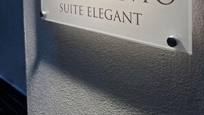 Un letrero que dice 'Montesanto Suite Elegant', con un logotipo que muestra una corona y una corona de laurel.