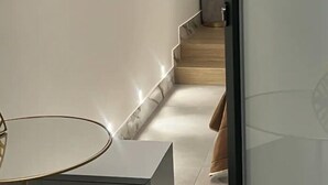 Un interior moderno con una escalera minimalista, una puerta de cristal con un monograma y una paleta de colores blancos y limpios.