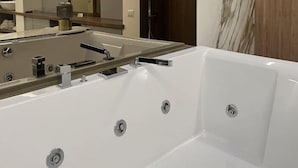 Un baño moderno con un espejo grande, una bañera y una ducha a pie.