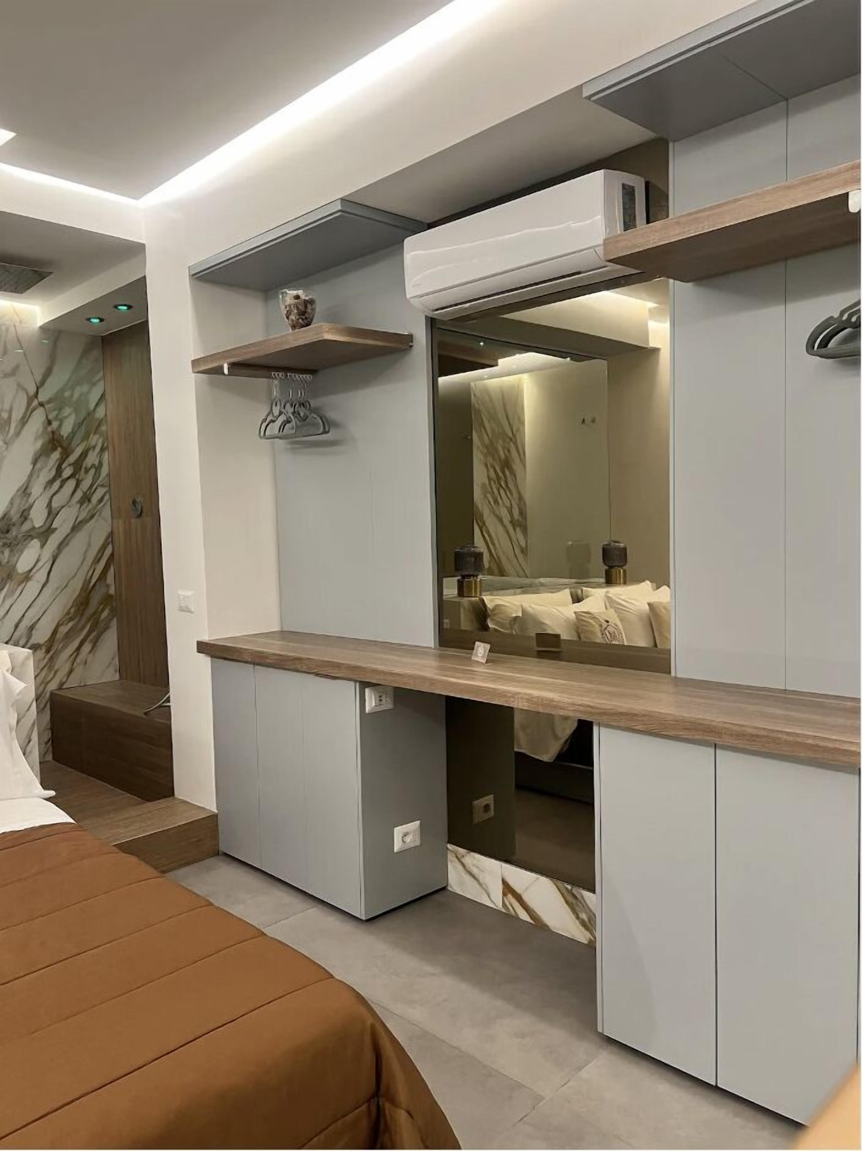 A modern bedroom with built-in storage, a vanity with a mirror, and a marble-patterned wall.