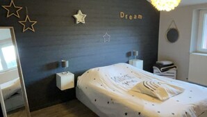 Een slaapkamer met een bed, nachtkastjes, een hanglamp, een ster decoratie en een raam.
