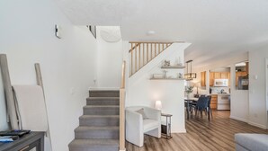 Un espacio habitable moderno con una escalera, comedor y cocina.