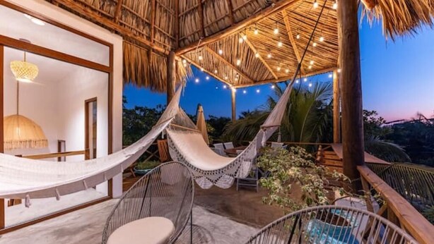 A hammock under a thatched roof, wicker chairs, and a view of the surrounding landscape. - Entire villa for 8 people (El Paredon)