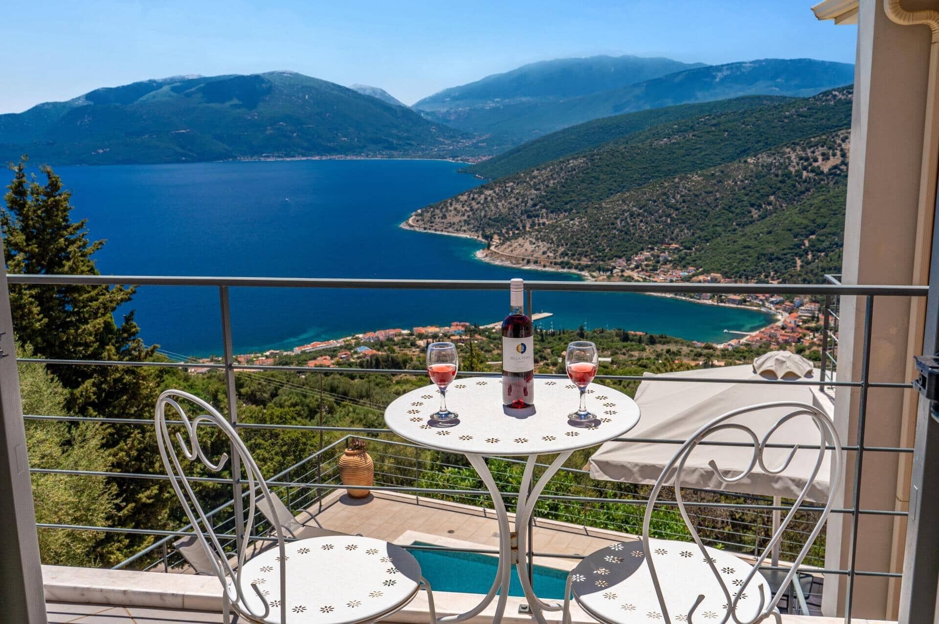 Un balcón con mesa y sillas que ofrece vistas panorámicas de un lago y montañas.
