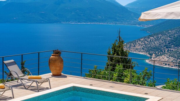 Ein Poolbereich mit Blick auf ein großes Gewässer und Berge.