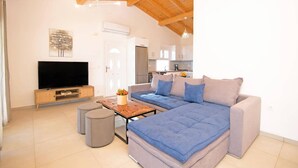 Un salon moderne avec un canapé d’angle, un téléviseur à écran plat et un coin repas comprenant une table et des chaises.