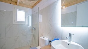 Une salle de bain moderne avec une douche à parois de verre, des toilettes et un lavabo surmonté d’un miroir.