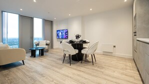 A modern living room with a dining area, large windows, and a flat-screen TV. - Nuvola Suite by Casacity (Manchester)