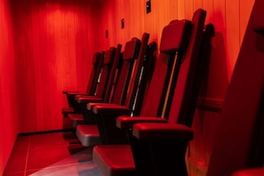 A row of red theater-style chairs with wooden walls and a tiled floor. - Nuvola Suite by Casacity (Manchester)