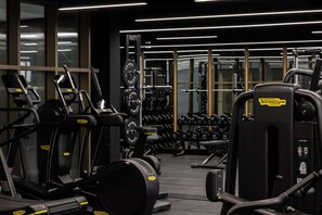 Ein Fitnessstudio mit Laufbändern, Krafttrainingsgeräten und Kurzhanteln.